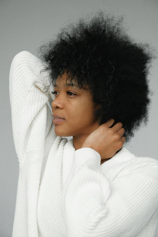 a woman in a white sweater adjusts her hair, by Lily Delissa Joseph, trending on pexels, renaissance, short black curly hair, collar on neck, tired expression, black on white