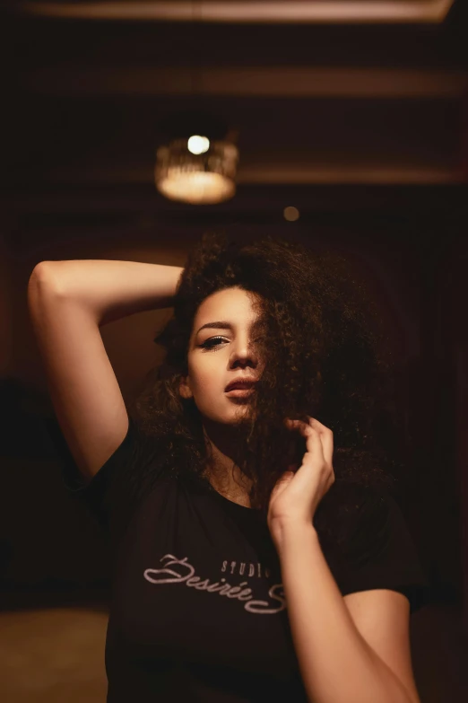 a woman with curly hair wearing a black shirt, inspired by Elsa Bleda, pexels contest winner, late night, regal pose, cynthwave, olive skinned