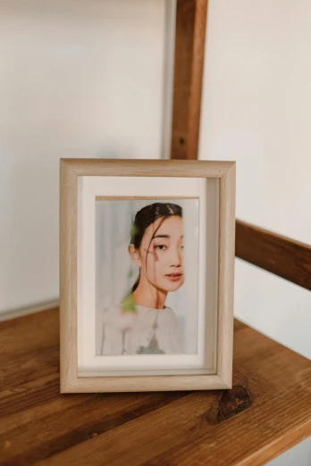 a picture of a woman sitting on top of a wooden table, a polaroid photo, by Tan Ting-pho, unsplash, hyperrealism, framed poster, young adorable korean face, displayed on an altar, 4 k product photo