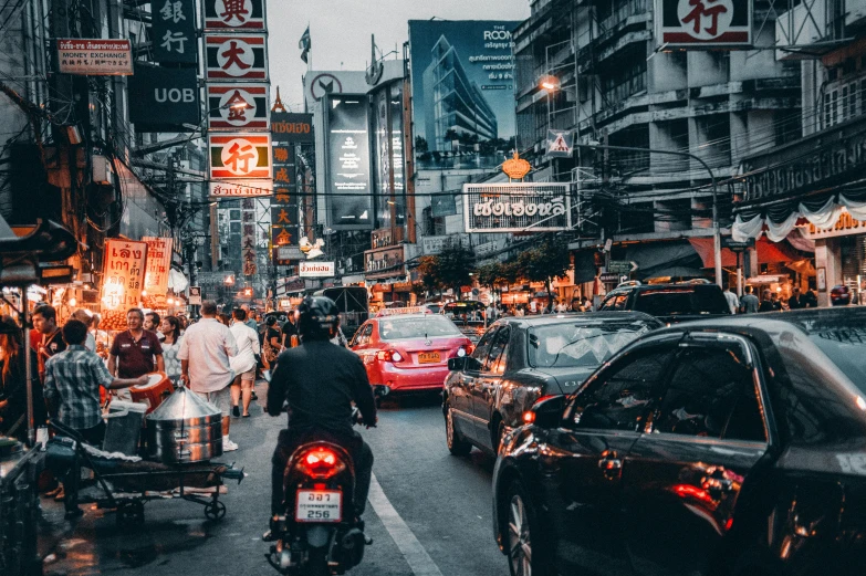 a man riding a motorcycle down a busy street, pexels contest winner, thailand art, square, cars parked underneath, 🦩🪐🐞👩🏻🦳