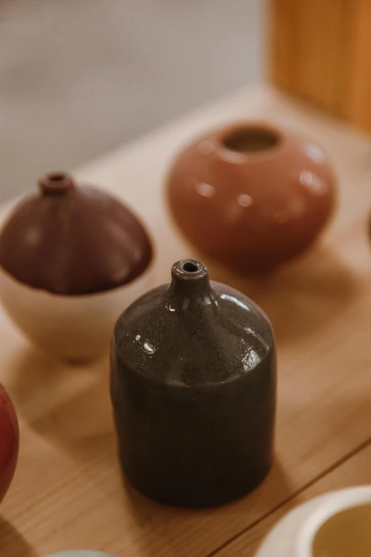 a group of vases sitting on top of a wooden table, trending on unsplash, mingei, burnt umber, close-up product photo, detailed product image, small