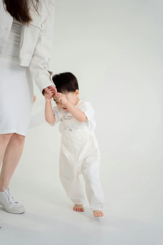 a woman holding the hand of a small child, by Katsukawa Shun'ei, unsplash, mingei, white trendy clothes, studio photoshoot, walking boy, off - white collection