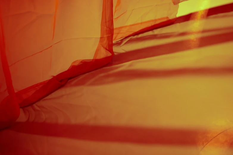 a bed with a mosquito net on top of it, inspired by Christo, unsplash, lyrical abstraction, redscale photography, gold and red, tents, high shadow