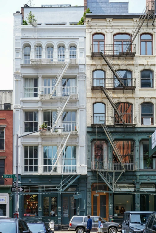 a group of cars driving down a street next to tall buildings, a photo, inspired by Donald Judd, renaissance, outdoor staircase, tenement buildings, architectural digest, with an intricate