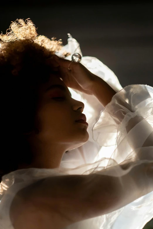 a woman in a white dress posing for a picture, inspired by Gordon Parks, trending on pexels, light and space, imaan hammam, waking up, soft backlighting, a glowing halo