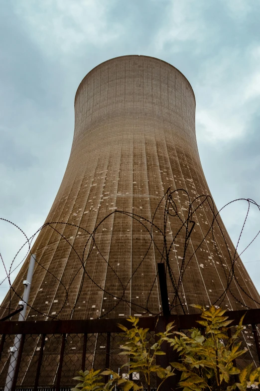 a cooling tower with barbed wire around it, by Dan Scott, unsplash, nuclear art, # nofilter, alabama, lead - covered spire, 2022 photograph