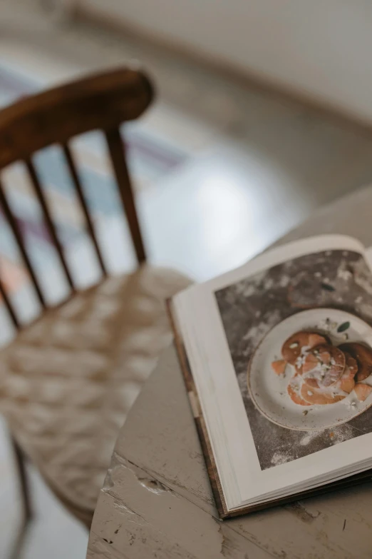 an open book sitting on top of a wooden table, a still life, trending on unsplash, visual art, over a dish and over a table, covered in white flour, portrait picture, gif