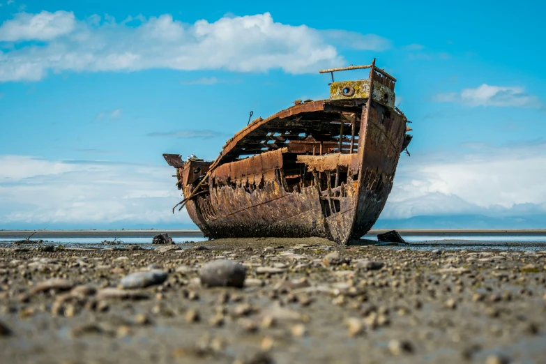 a rusted ship sitting on top of a sandy beach, crumbling, ash thorp, top selection on unsplash, built on a small