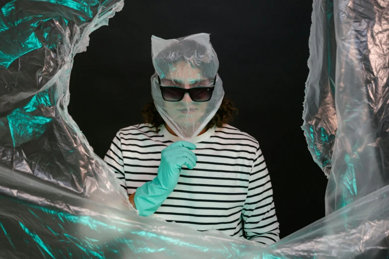 a woman in a black and white striped shirt and green gloves, an album cover, pexels contest winner, plasticien, see through glass hologram mask, wearing lab coat and glasses, wearing a plastic garbage bag, white and teal garment