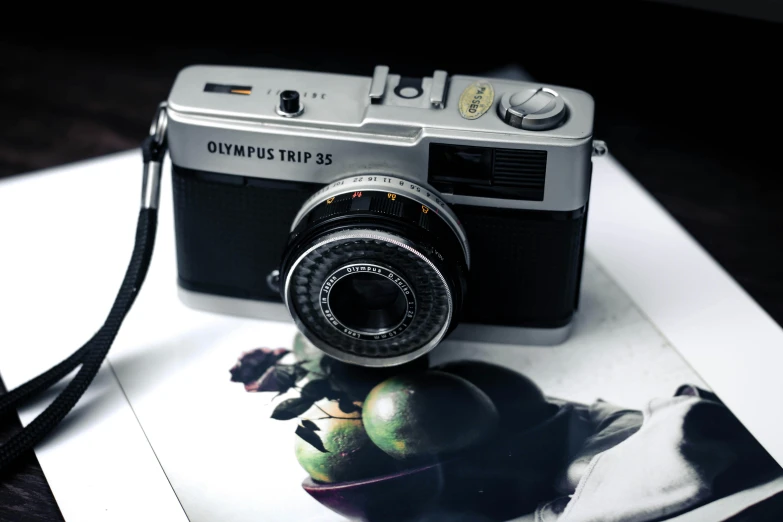 a camera sitting on top of a piece of paper, a photorealistic painting, inspired by Yasushi Sugiyama, unsplash contest winner, hyperrealism, olympus platform, ((still life)), vintage photo, olympus