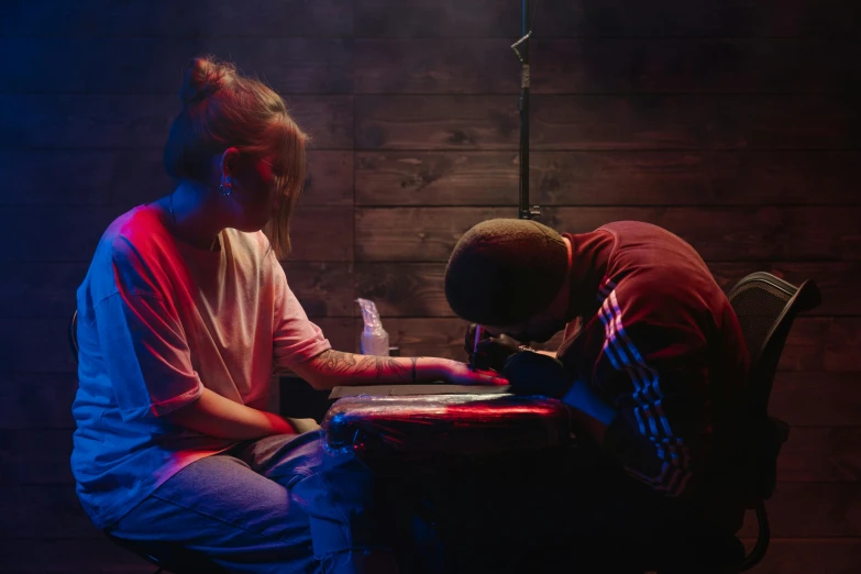 a couple of people that are sitting at a table, a tattoo, inspired by Elsa Bleda, pexels contest winner, process art, red and blue lighting, turntablist, very faded, an escape room in a small