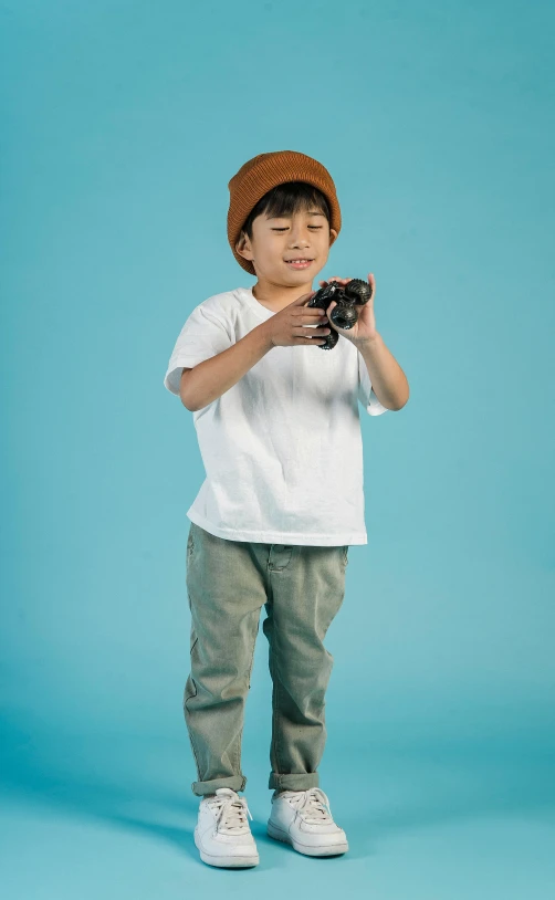 a young boy taking a picture with a camera, inspired by Jean Tabaud, pexels, holding controller, caracter with brown hat, toy commercial photo, wearing casual clothing