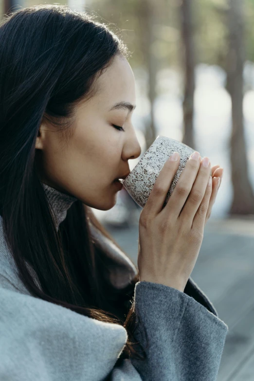 a woman is drinking a cup of coffee, trending on pexels, renaissance, sydney park, made of glazed, bark for skin, grey