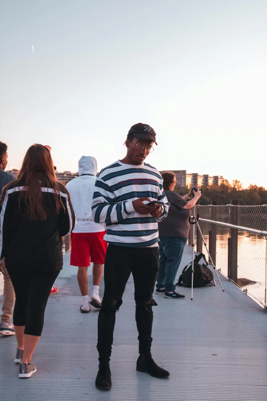 a group of people standing on top of a bridge, looking at his phone, chillhop, ready to model, sundown