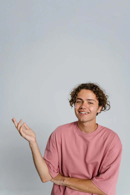 a man in a pink shirt sitting on a skateboard, trending on pexels, brown curly hair, shrugging, profile picture, connor hibbs