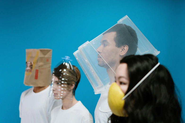 a group of people standing in front of a blue wall, trash bag on head, wearing transparent glass mask, like a catalog photograph, fluid bag