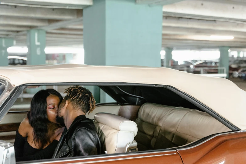 a man and a woman kissing in a car, by Dan Frazier, trending on pexels, visual art, set inside of parking garage, nipsey hussle, leather interior, miami vice