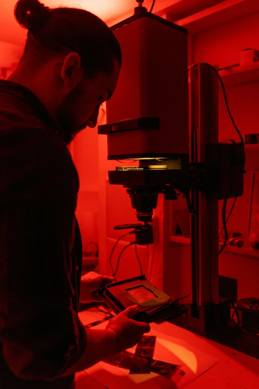 a man standing in front of a red light, a microscopic photo, in a lab, digging, atmospheric red lighting, profile pic