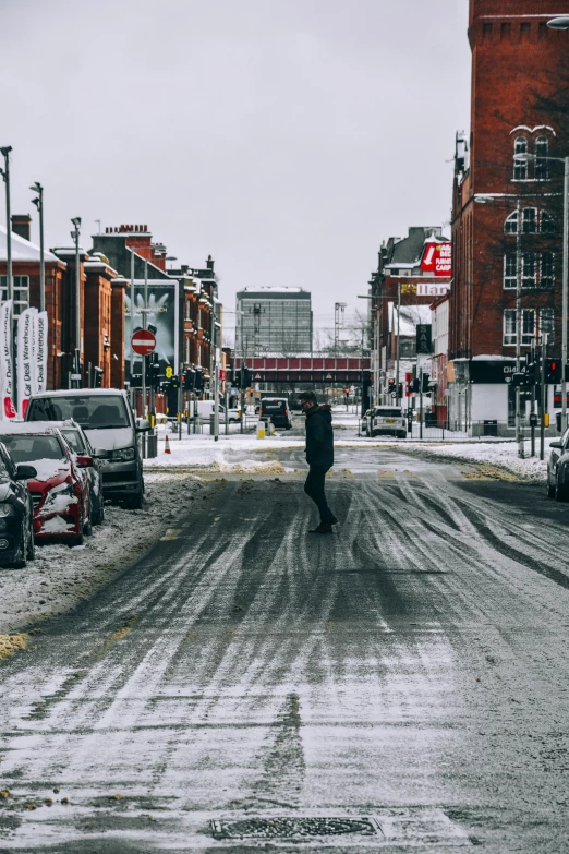 a person walking down a snow covered street, manchester, clean streets, thumbnail, gritty