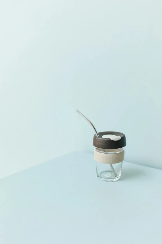 a cup of coffee with a spoon in it, unsplash, minimalism, glass jar, beige, rendered in corona, silicone skin