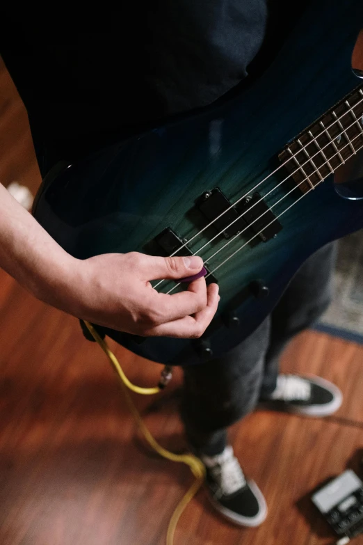 a person playing a guitar on a hard wood floor, blue veins, bass sound waves on circuitry, promo image, student