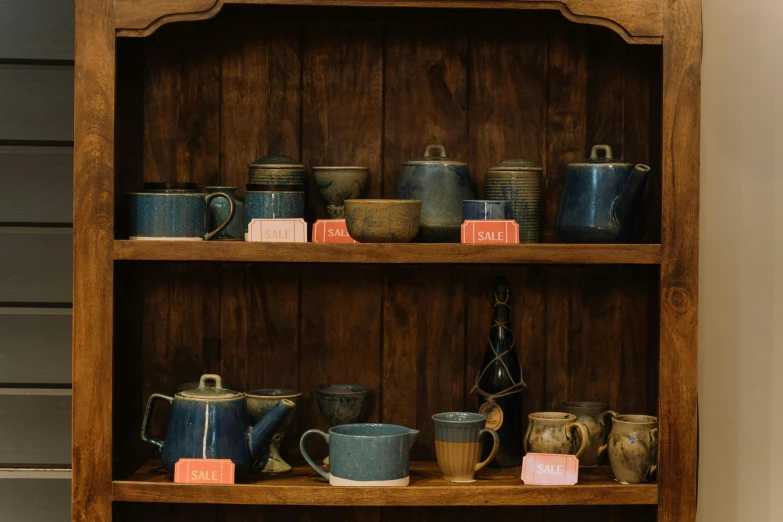 a wooden shelf with cups and mugs on it, by Hannah Tompkins, unsplash, dipped in polished blue ceramic, in a potion shoppe, slight overcast lighting, thumbnail