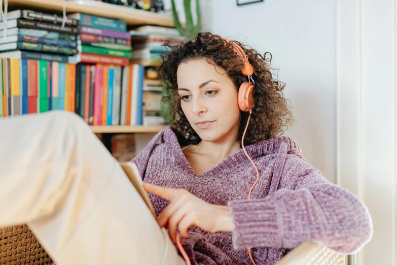 a woman sitting in a chair with headphones on, trending on pexels, happening, from reading to playing games, wearing a pink hoodie, woman with braided brown hair, thumbnail