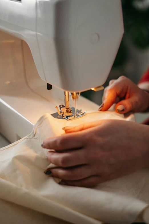 a close up of a person using a sewing machine, in the evening