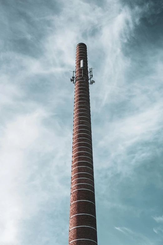 a tall brick tower sitting on top of a lush green field, by Carey Morris, unsplash, conceptual art, industrial pipes, long antennae, profile image, show from below