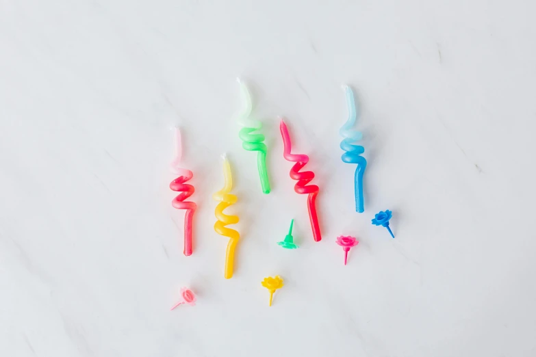 a group of toothbrushes sitting on top of a counter, an airbrush painting, by Nicolette Macnamara, crayon art, plasticized spiral flames, party balloons, (neon colors), dipstick tail