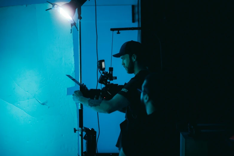 a man that is standing in front of a camera, inspired by Elsa Bleda, pexels contest winner, video art, cinematic blue lighting, behind the scenes, action shot, practical effects