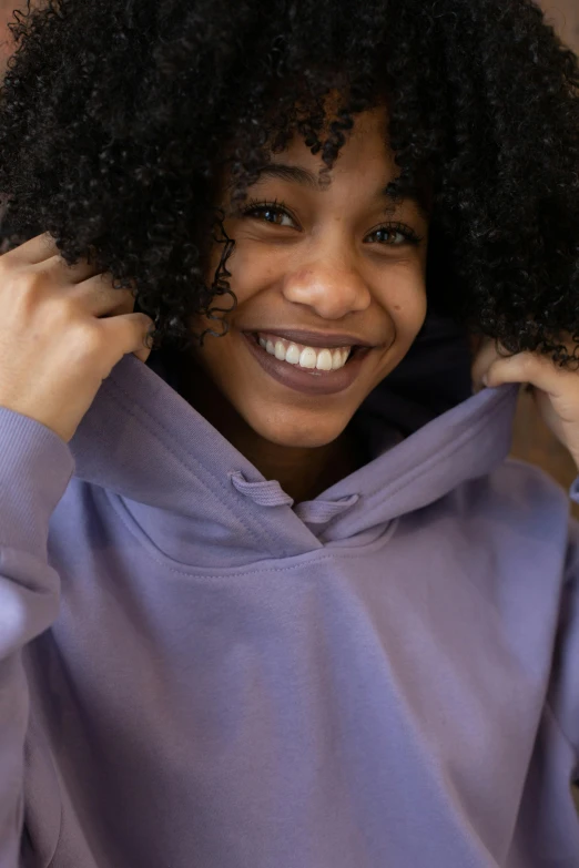 a close up of a person wearing a hoodie, lilac, afro, smiling down from above, wearing a grey hooded sweatshirt