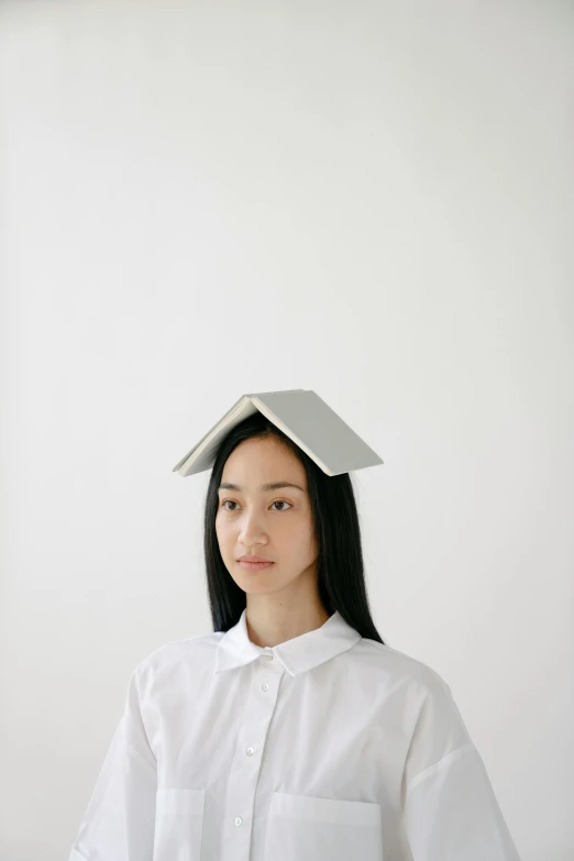 a woman in a white shirt with a book on her head, by Mei Qing, simple gable roofs, designer product, naoya tanaka, grey