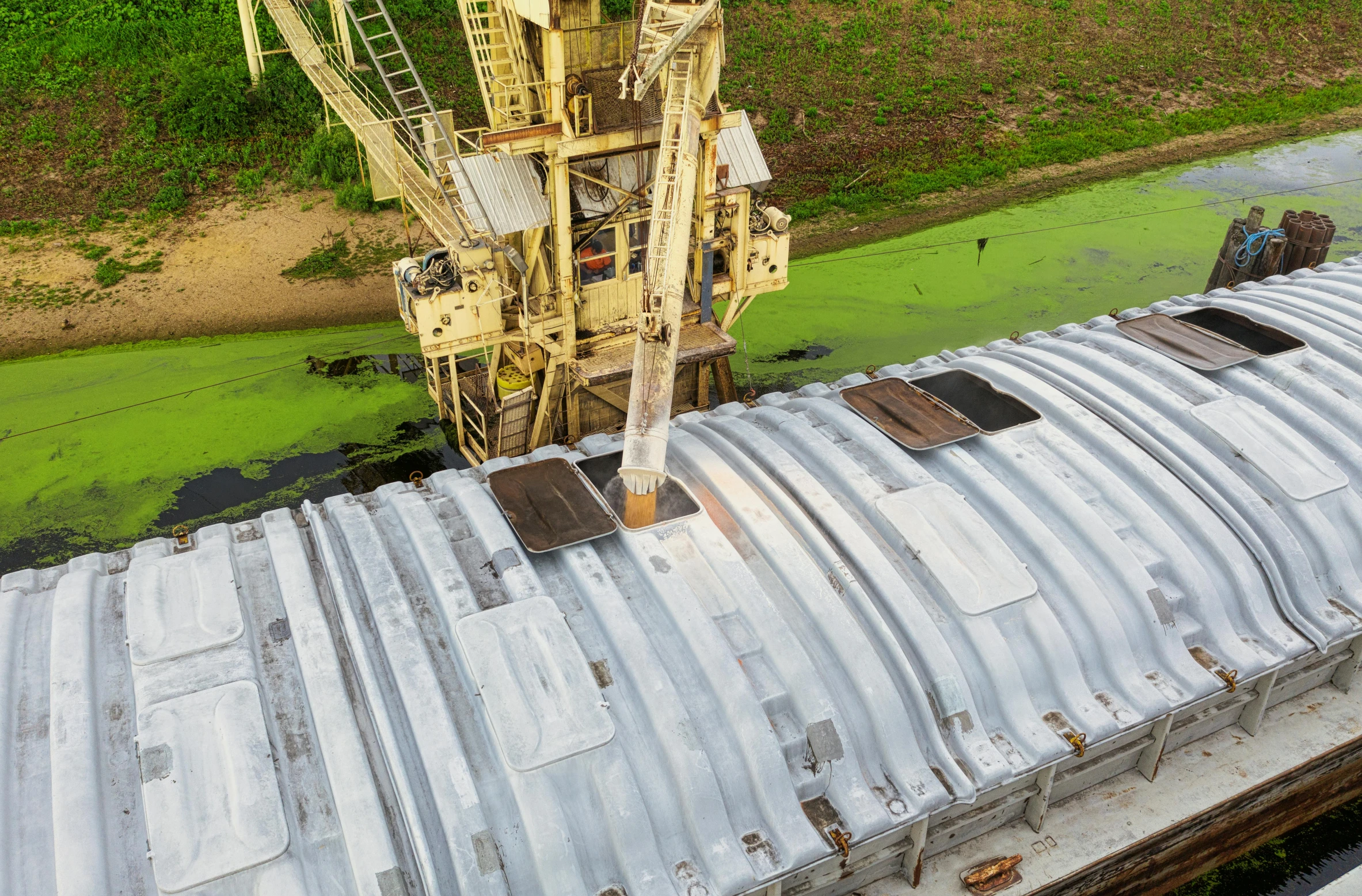 a crane sitting on top of a roof next to a body of water, plasticien, wide overhead shot, bioremediation, thumbnail, silo