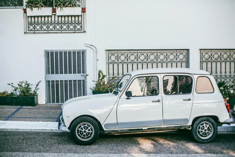 a small white car parked in front of a building, by Carey Morris, pexels contest winner, directoire style, square, white concrete, at home