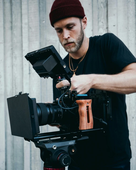 a man standing next to a camera on a tripod, by Adam Rex, unsplash contest winner, video art, holding a mp7, graded with davinci resolve, close up portrait shot, red cinema camera