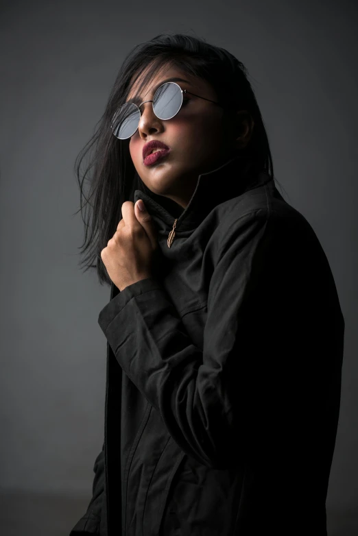 a woman in a black jacket and sunglasses, by Ric Estrada, asian female, underexposed grey, studio shoot, in style of lam manh