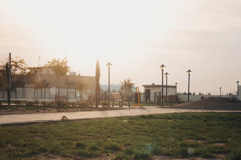 a red fire hydrant sitting on top of a lush green field, a picture, by Attila Meszlenyi, unsplash, realism, street lamps with orange light, at a skate park, in a sunset haze, summer street near a beach