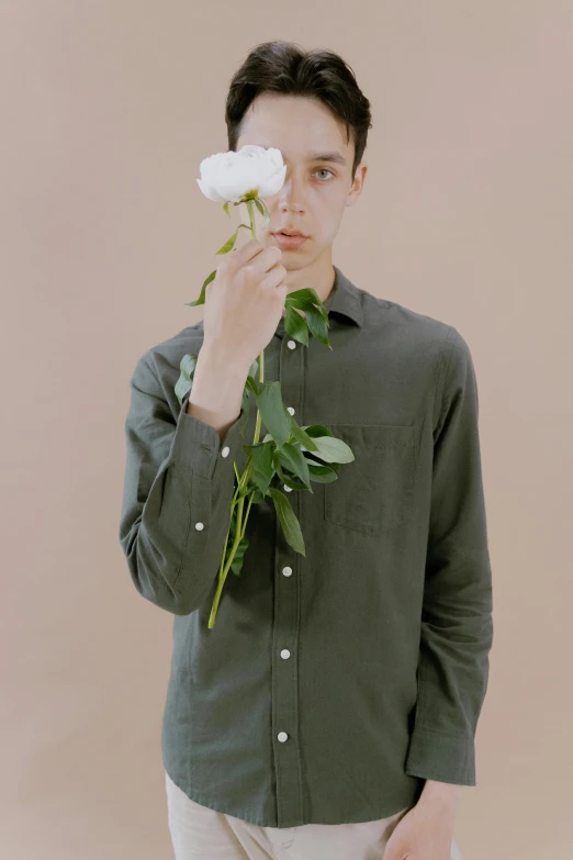 a man holding a white rose in front of his face, an album cover, inspired by Jean Malouel, trending on unsplash, full body full height, green shirt, linen, daniel oxford