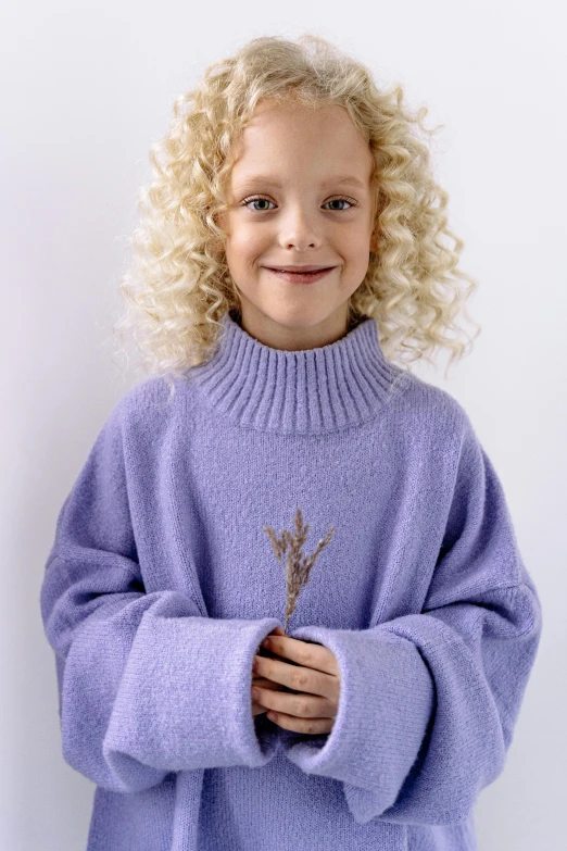 a little girl with blonde hair wearing a purple sweater, inspired by Violet Fuller, trending on pexels, curly blonde hair | d & d, pastel blue, product introduction photo