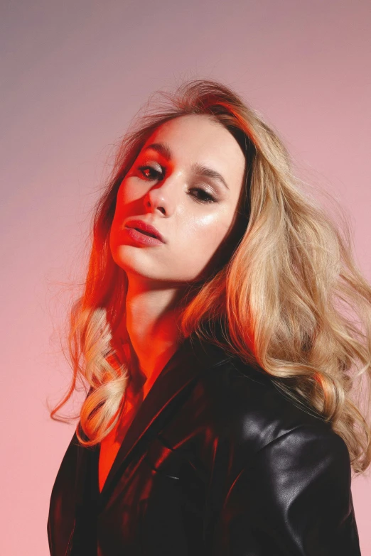 a woman with long blonde hair wearing a black jacket, an album cover, by Sara Saftleven, trending on pexels, handsome girl, studio picture, portrait sophie mudd, vibrant glow