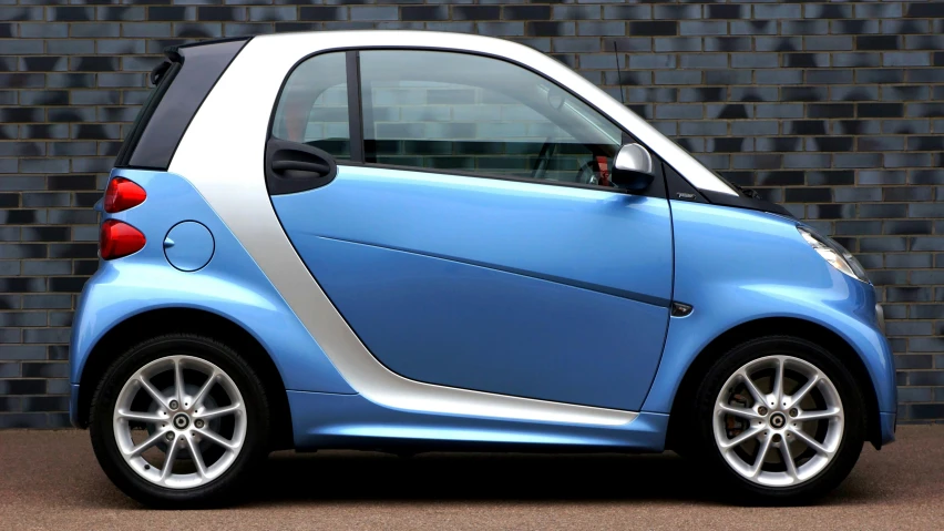 a smart car parked in front of a brick wall, by Carey Morris, pixabay, sky blue and white color scheme, side profile, square, blue silver and black