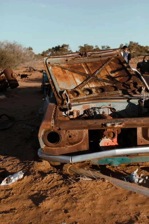 a rusted out car sitting on top of a dirt field, on the desert, tools and junk on the ground, 2019 trending photo, holes