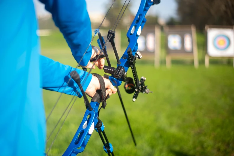 a close up of a person holding a bow, strong blue rimlit, sports setting, 🦩🪐🐞👩🏻🦳, exterior shot