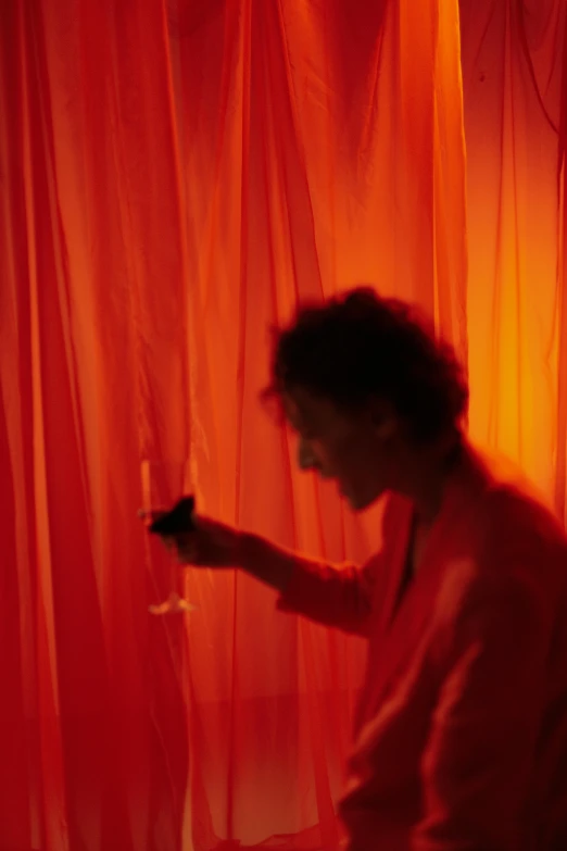 a man holding a wine glass in front of a red curtain, inspired by Nan Goldin, vanitas, coloured in orange fire, ethereal curtain, maya deren, ignant