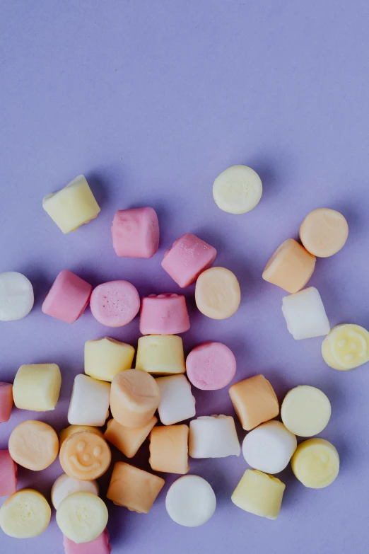 a pile of marshmallows on a purple background, a picture, by Justin Sweet, unsplash, square shapes, cheeses, gumdrops, orange pastel colors