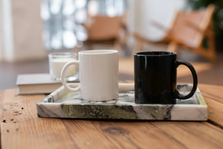 two coffee mugs are sitting on a marble tray, trending on unsplash, dezeen showroom, square, product display photograph, black