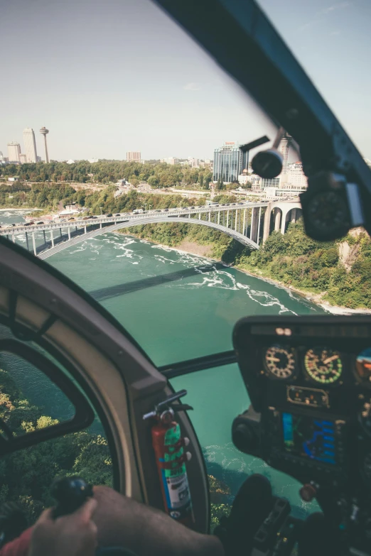 a view of a bridge from inside a helicopter, niagara falls, skyline showing from the windows, in cockpit