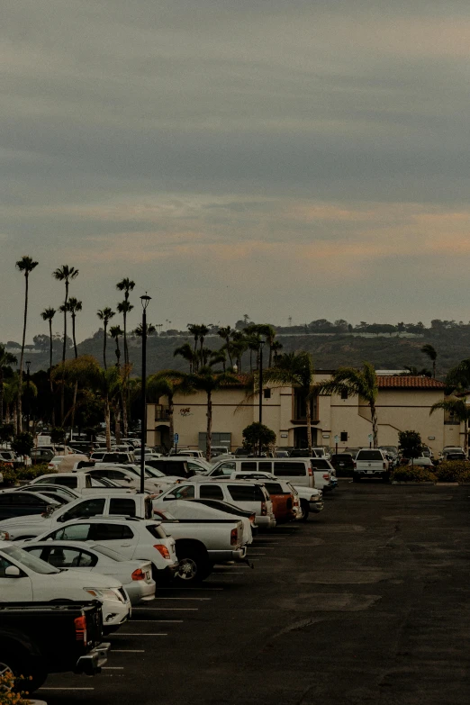 a parking lot filled with lots of parked cars, a portrait, by Robbie Trevino, renaissance, sunset panorama, oceanside, gray skies, high quality photo