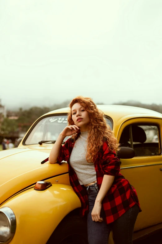 a woman leaning on the hood of a yellow car, a colorized photo, pexels contest winner, curly red hair, beetle-inspired, instagram picture, a young asian woman